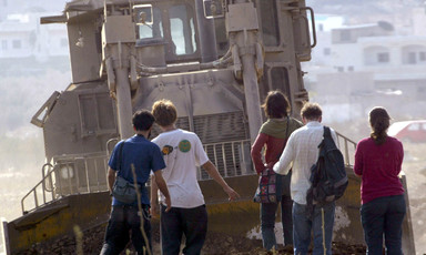 A group of people appears small next to an armored bulldozer