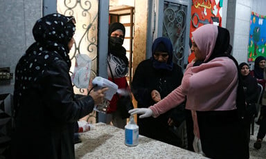 A woman sprays another woman's hands as two women look on