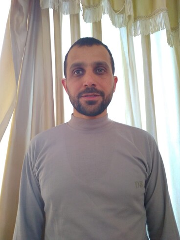 Man stands with window behind him.