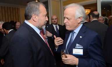 Two men talk together at conference with people in background
