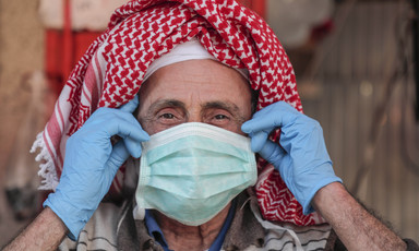 Man wearing headscarf adjusts protective mask on his face