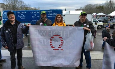 People stand with QAnon banner