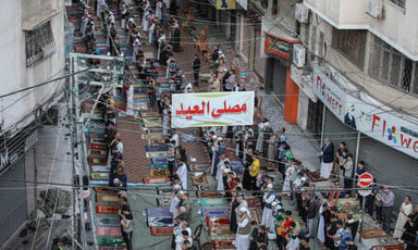 Aerial view of men praying on a shop-lined street
