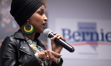 Woman holds microphone with one hand and gestures with the other