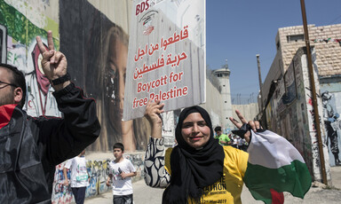 A woman makes a victory sign while holding a poster