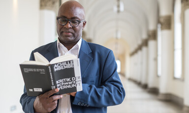 A standing man reads a book