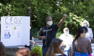 Masked man with raised fist along with masked crowd