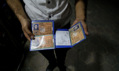 A man holds temporary ID cards that are void for travel.