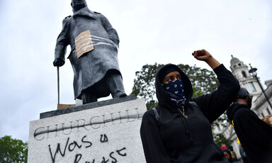 Woman stands in front of statue and clenches fist 