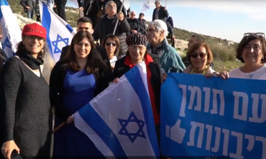 A group of people with Israeli flags and a banner in Hebrew