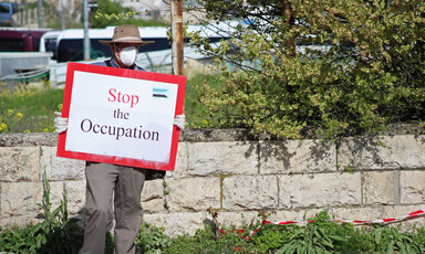 Man wears protective mask and holds sign
