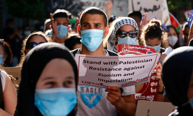 People wearing protective masks hold signs at protest 