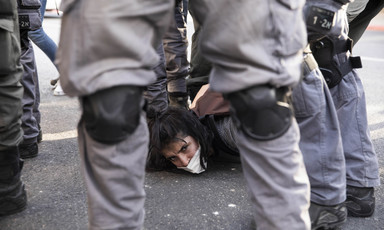 Israeli police stand around woman on ground looking toward camera