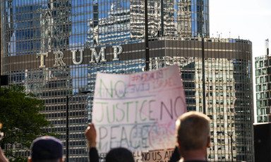People hold protest signs in front of Trump building