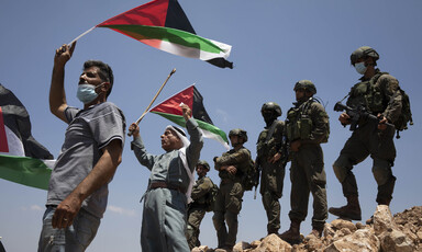 Men wave flags in front of soldiers 