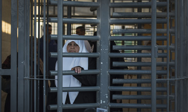 A woman pushes at the metal bars of a caged turnstile