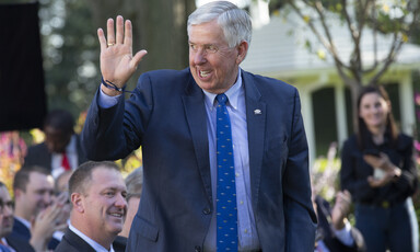 A man in a suit waves his hand