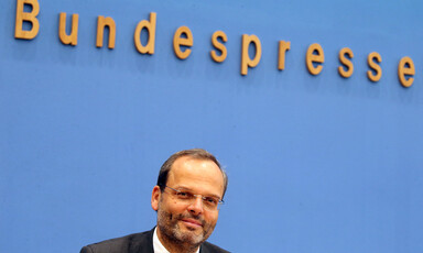 Smiling man sits a press podium