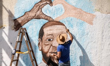 A man paints a mural on a wall in Gaza