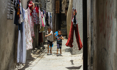 Two children play in a narrow alley where washing has been hung