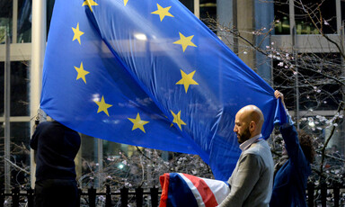 Two people hold a flag with stars 