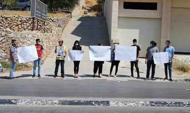 People stand next to each other on the street holding signs