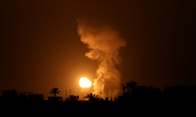 Flame and smoke rise from landscape in the dark 