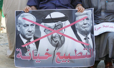 Man holds banner with three men on it