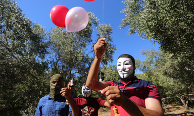 Man with mask holds a number of balloons 