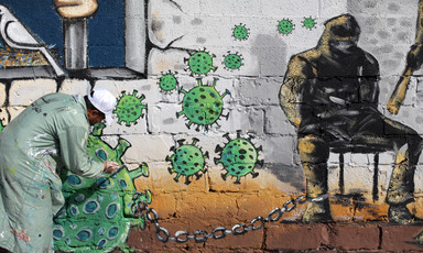 Man paints wall with images representing the virus and prisoners