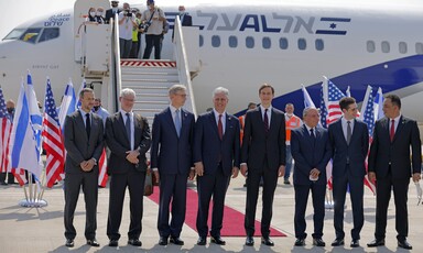 Men in suits stand in one line before airplane 