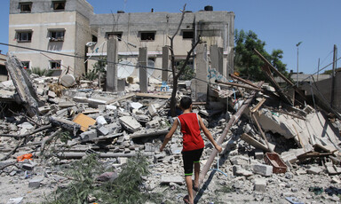 Boy stands in the remains of a badly damaged building 