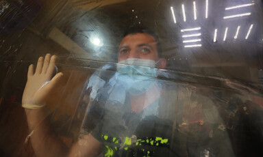 Man in mask places gloved hand on protective screen