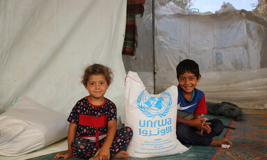 Two children sit on the ground 