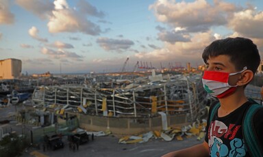 Boy stands in front of landscape of destroyed buildings