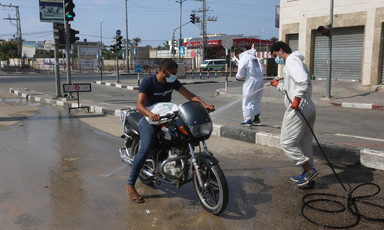 Man wearing white hoses down a motorcycle 