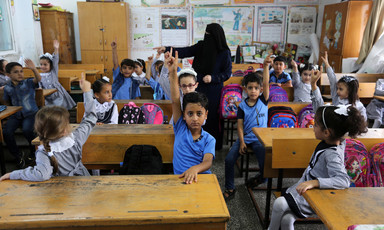 Children raise their hands in a classroom