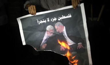 Man holds burning poster of two men 