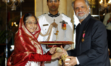  Man receives object from woman as ceremonial guard looks on