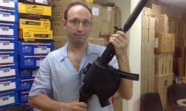 A man in glasses poses with a rifle