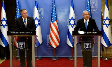 Two men stand at podiums with US and Israeli flags behind them