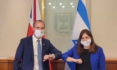 A man and a woman in masks touch elbows