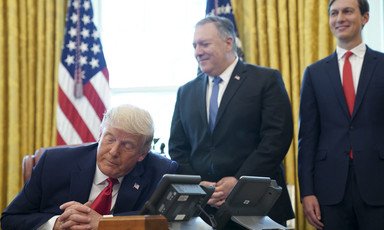 Man sits on a desk surrounded by others 