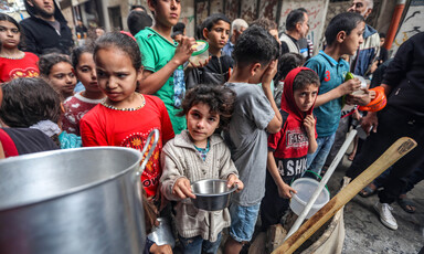 Children stand while holding empty bowls