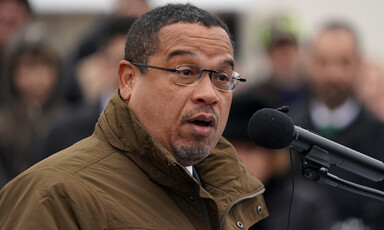 Man in winter coat speaks at microphone