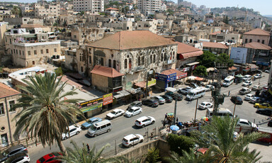 A view over a city, with buildings, traffic and just two trees