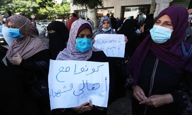 Women in face masks carry posters during a protest