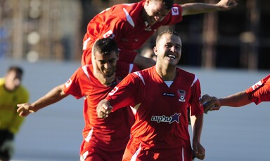 Man jumps in the air as two other men run, smiling 