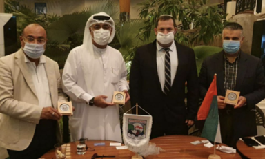 Four mean wearing protective masks hold plaques