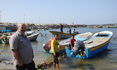 Three men stand near fishing vessels